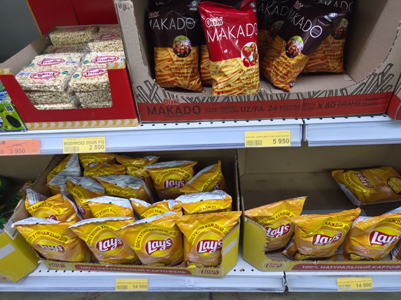Полки с чипсами Lay's «Сыр», картофельной соломкой Oishi Makado, снеками «Хрустика» и жёлтыми ценниками