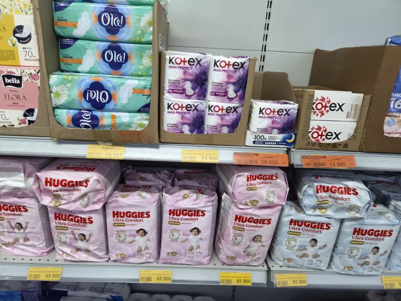 Havas: полки с прокладками Ola!, Kotex Maxi Protect и Kotex Deo (оранжевые ценники CHEGIRMA на Kotex Ultra Night и Deo); ниже Huggies Ultra Comfort для девочек и мальчиков