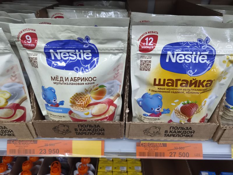 Полка Havas: детская каша Nestle «Мёд и абрикос» (с 9 месяцев) и «Шагайка» с земляникой, яблоком и малиной (с 12 месяцев), под ними два акционных ценника Chegirma