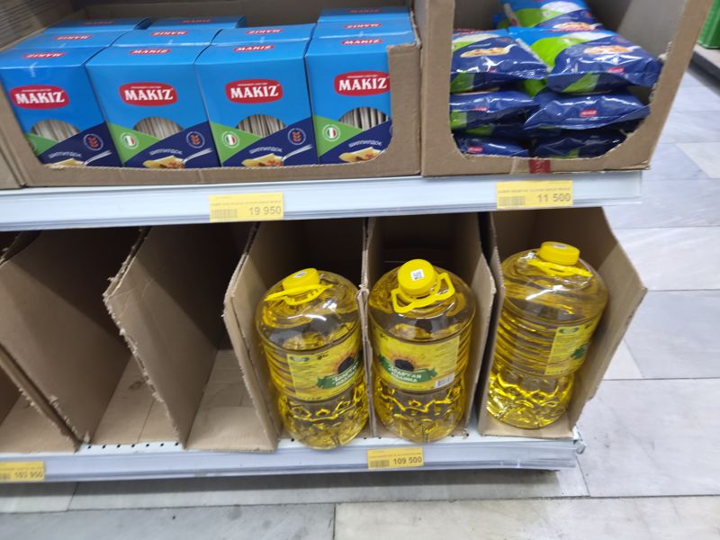 Havas: макароны Makiz в коробках, нижняя полка с подсолнечным маслом Золотая поляна в бутылках 5 л, жёлтые ценники (кадр смазан)