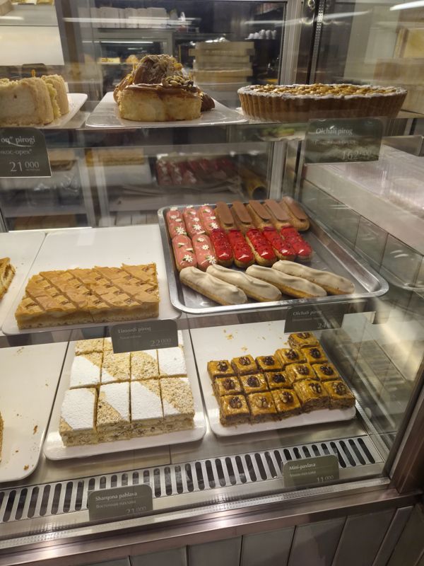 Витрина Cakelab: вишнёвый тарт целиком, эклеры с розовой, красной, шоколадной и белой глазурью, пироги, пахлава с грецким орехом и кокосовый торт