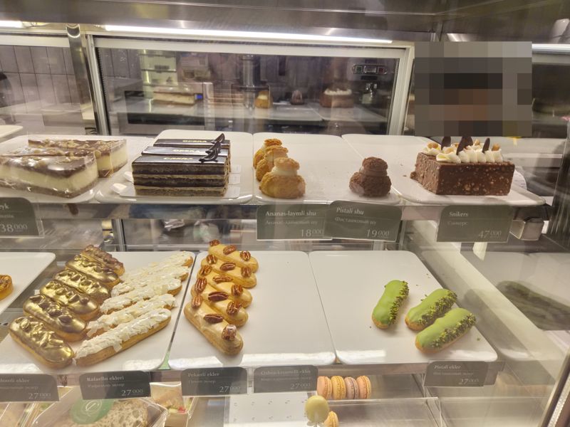 Витрина Cakelab: чизкейк, торт «Опера», шу ананас-лайм и фисташковый, торт «Сникерс», эклеры золотые, «Рафаэлло», с пеканом, кофе-карамельные и фисташковые, макаронс