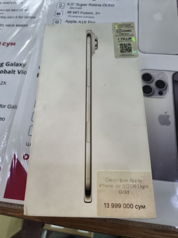 Коробка смартфона Apple iPhone Air с наклейкой-ценником магазина; на заднем плане распечатки характеристик с ценами в плёнке