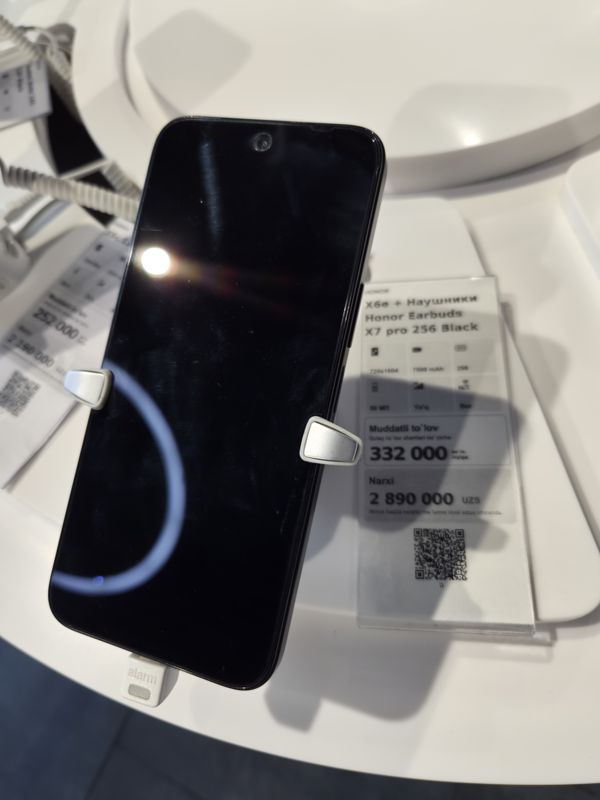 Смартфон в держателе на витрине Ucell, рядом ценник-комплект: HONOR X6e + наушники Honor Earbuds X7 pro 256 Black, 2 890 000 сум