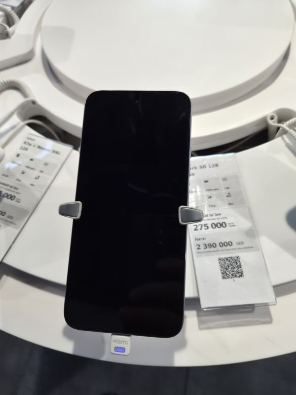 Смартфон Tecno Spark 50 в держателе с сигнализацией на витрине Ucell, рядом ценник-карточка: Spark 50 128 Blue, 7000 мАч, цена 2 390 000 сум
