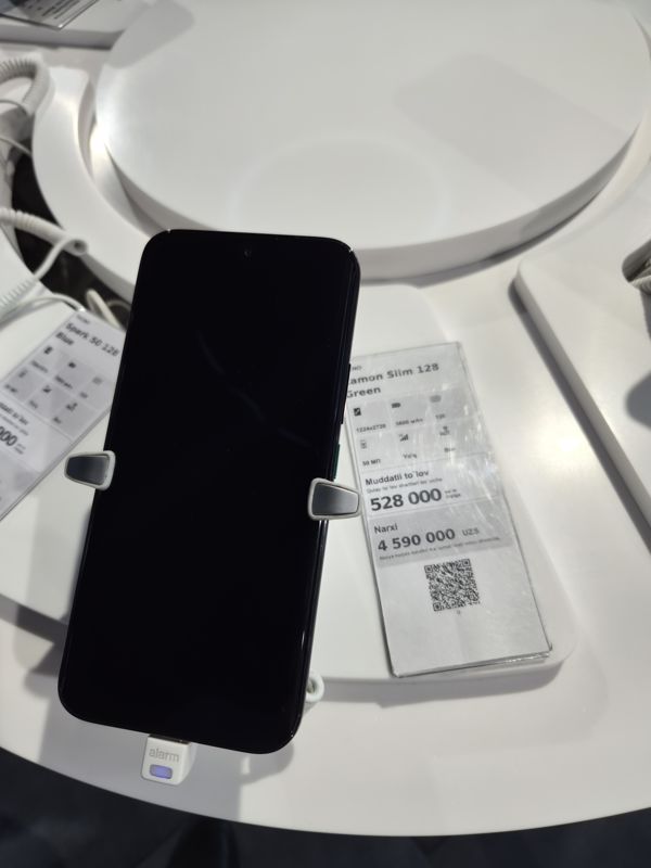 Смартфон Tecno Camon Slim в держателе на витрине Ucell, рядом ценник-карточка: TECNO Camon Slim 128 Green, 4 590 000 сум