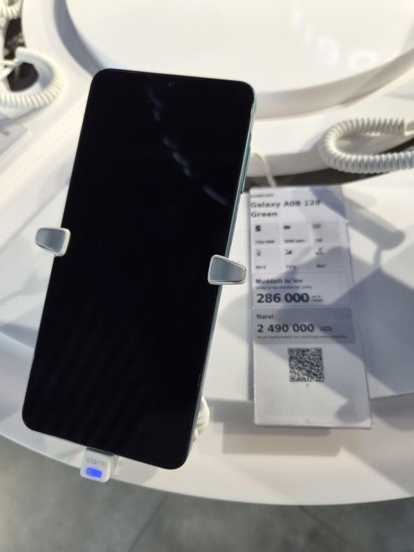 Смартфон Samsung Galaxy A08 в держателе на витрине Ucell, рядом ценник-карточка: SAMSUNG Galaxy A08 128 Green, 2 490 000 сум