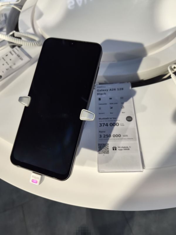 Смартфон Samsung Galaxy A26 на подставке с ценником Ucell: плашка «Maxsus aksiya» и подарок «5G cheksiz, 3 oyga 100GB»