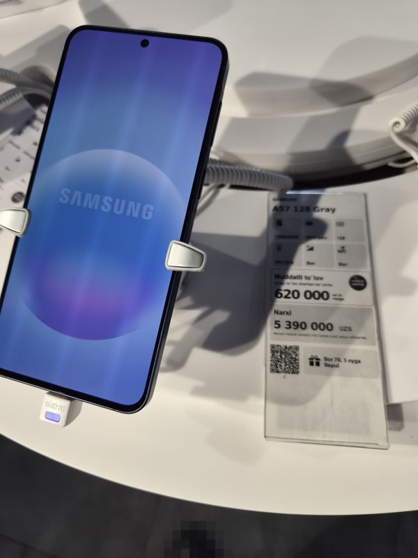 Смартфон Samsung A57 на подставке с ценником Ucell: плашка «Maxsus aksiya» и подарок «Bor 70, 3 oyga Bepul»