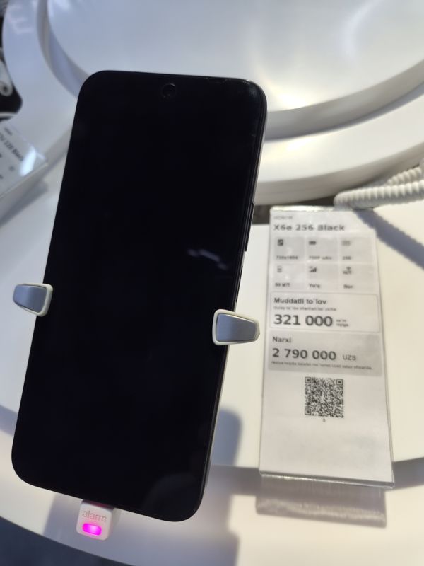 Смартфон Honor X6e 256 Black на стенде Ucell в держателе с сигнализацией, рядом ценник-карточка