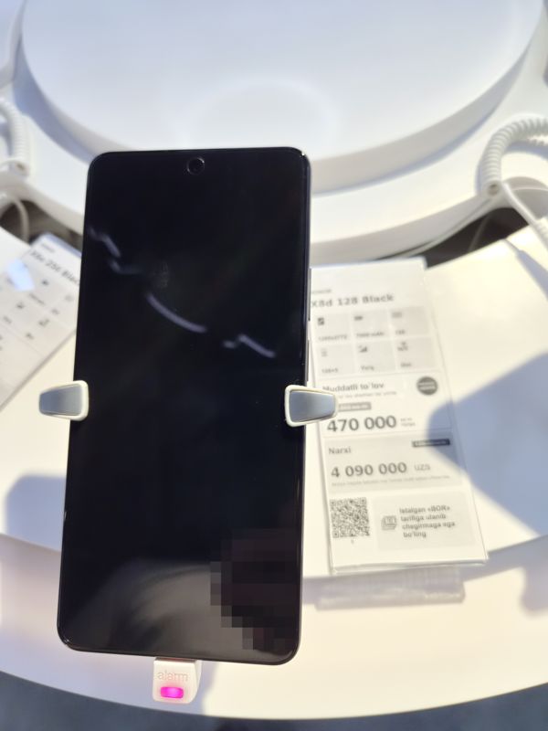 Смартфон Honor X8d 128 Black на стенде Ucell, справа ценник-карточка с круглой плашкой акции, слева ценник Honor X6e 256 Black