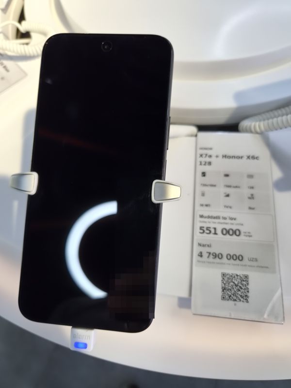 Смартфон Honor на стенде Ucell в держателе, справа ценник-карточка на комплект Honor X7e + Honor X6c 128