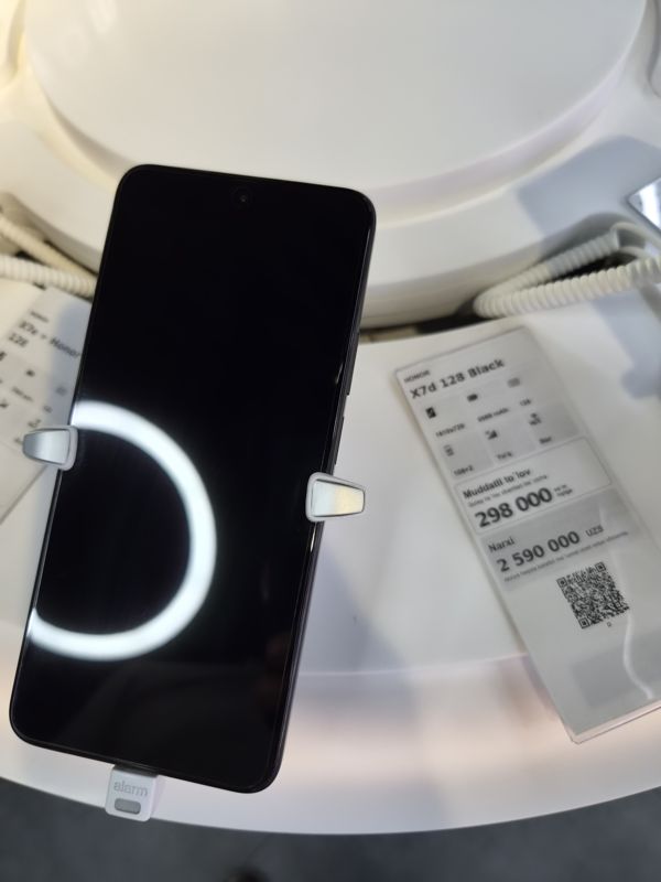 Смартфон Honor X7d 128 Black на стенде Ucell в держателе с сигнализацией, справа ценник-карточка