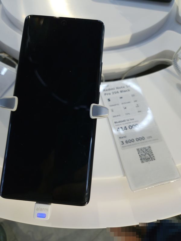 Смартфон Xiaomi Redmi Note 14 Pro 256 Black на стенде Ucell в держателе с сигнализацией, справа ценник-карточка