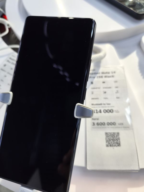 Демонстрационный смартфон Redmi Note 14 Pro на стойке Ucell с ценником «Redmi Note 14 Pro 256 Black», снимок не в фокусе