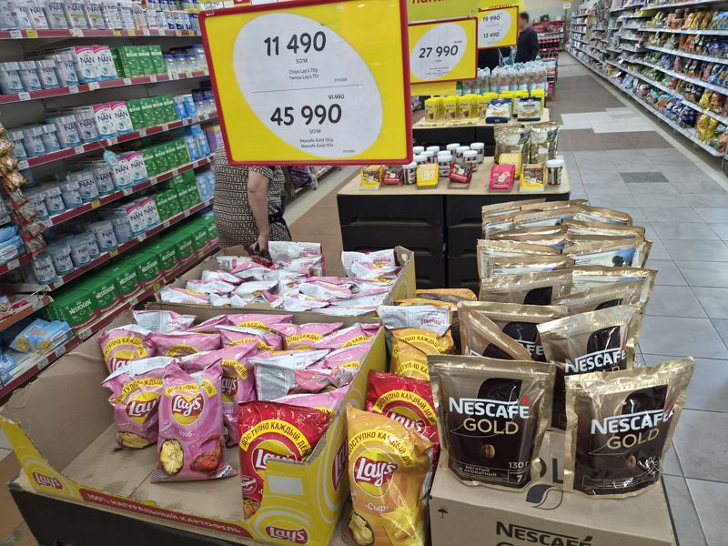 Горка с чипсами Lay's и кофе Nescafe Gold под двойным ценником, справа вдали шоколад Ritter Sport, Nutella и 7 Days