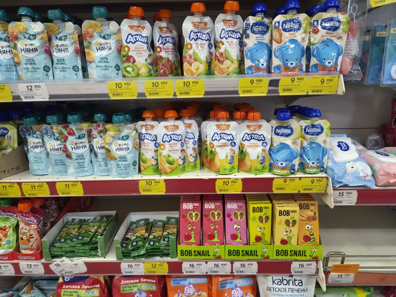 Нижние полки: пюре ФрутоНяня, Агуша, Nestle с ценниками; на нижней полке фруктовая пастила Bob Snail, батончики Gerber, влажные салфетки, детское печенье