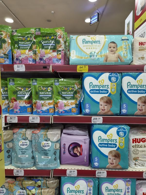 Детские каши Gipopo Natural и ФрутоНяня на полках, справа подгузники Pampers Active Baby и Premium Care, Huggies, Tomiko; полочные ценники