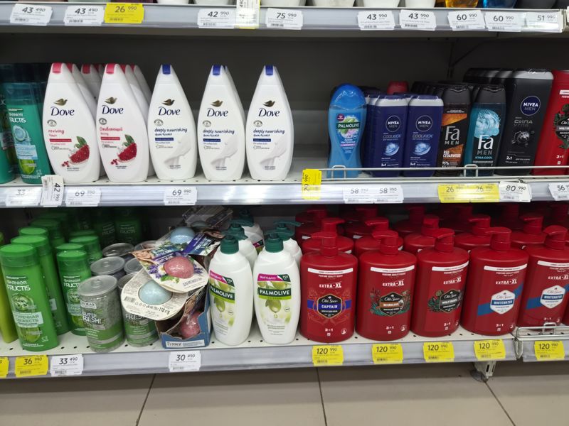 Стеллаж гелей для душа Dove, Fa, Nivea и Palmolive, шампуней Fructis, мужских гелей Old Spice Extra-XL; сверху и снизу белые и жёлтые подвесные ценники