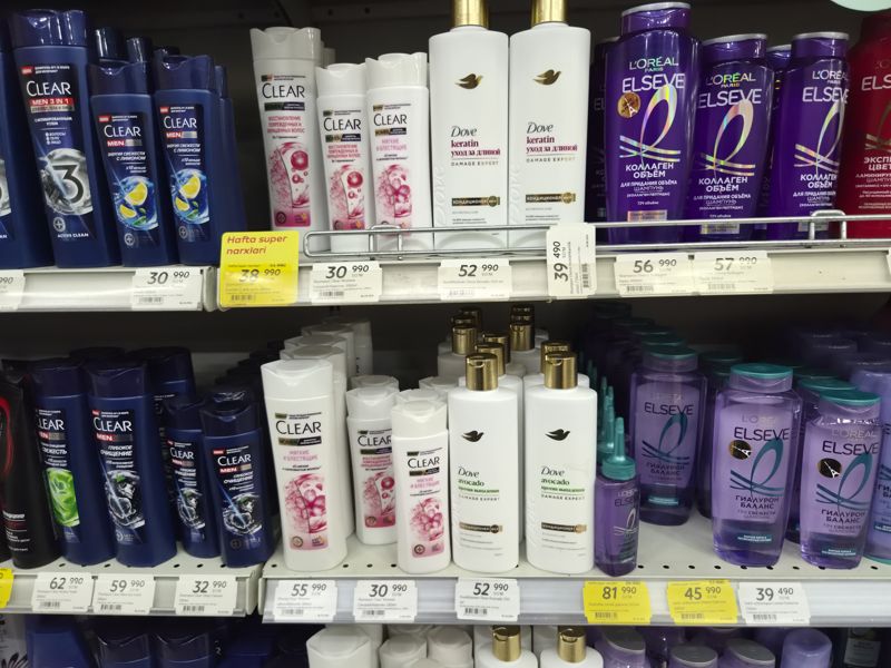 Стеллаж шампуней Clear Men и Women, кондиционеров Dove Damage Expert (Keratin, Avocado), Elseve Коллаген объём и Гиалурон Баланс; белые подвесные и жёлтые ценники «Hafta super narxlari»