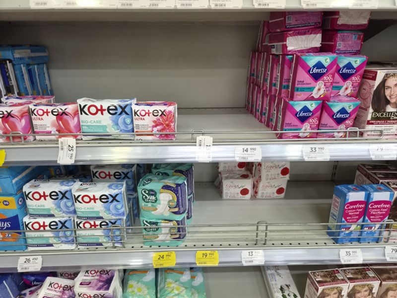 Полки гигиенических прокладок Kotex (Ultra, Bio-Care), Libresse Total Protection, Ola! Silk Sense, Freestyle Ultra; справа Carefree Cotton Feel; вверху краска L'Oreal Excellence; ценники на кромках, два жёлтых