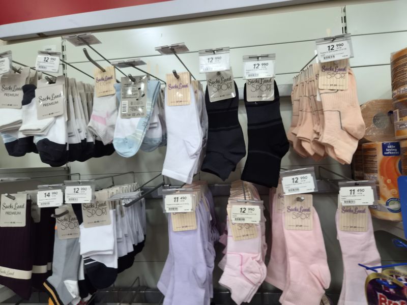 Стенд с носками Socks Land на крючках, ценники на навесных держателях; справа туалетная бумага Zewa