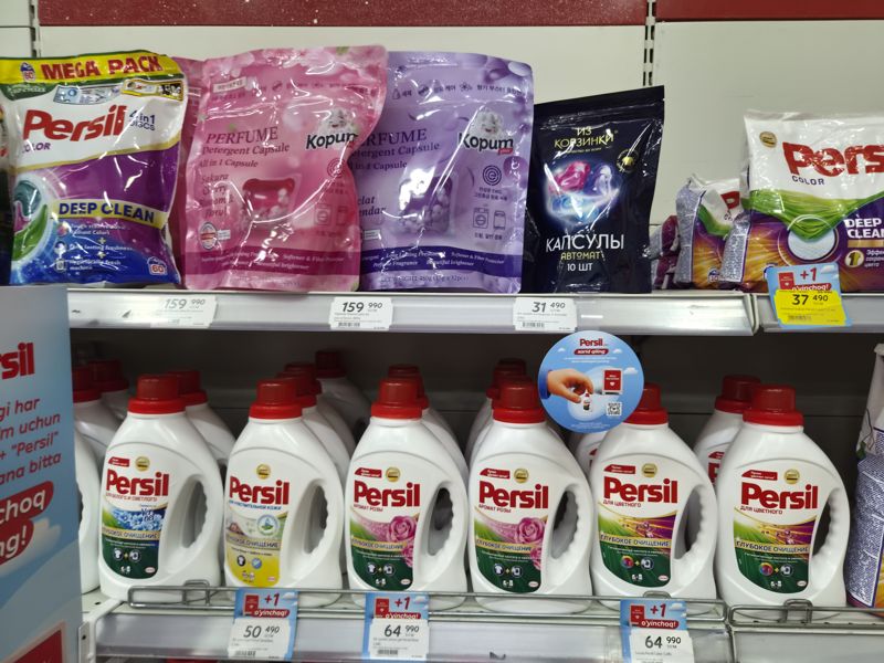 Полка с капсулами для стирки Persil 4 in 1, Kopum Plus, «Из Корзинки» и ряд жидких средств Persil (Sensitive, Rose, Color); ценники с наклейками +1 o'yinchoq