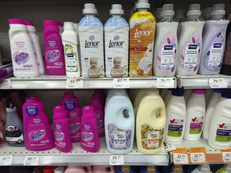 Полки с кондиционерами Lenor, Mayeri, Morni Flora, 365 kun и пятновыводителями Vanish, Mayeri; ценники на кромках, оранжевые «Aqlli tanlov» у 365 kun