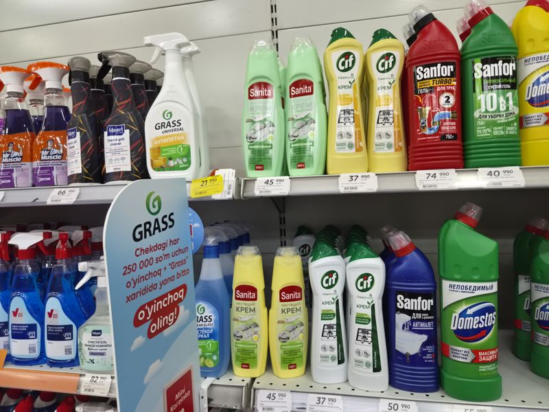 Полки с чистящими средствами Sanita, Cif, Sanfor, Domestos, Grass, Mayeri, Mr Muscle; ценники на кромках, жёлтый акционный Grass; слева стенд акции Grass + Mini Korzinka