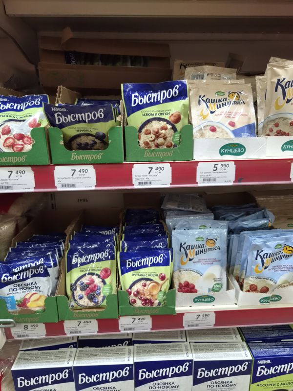 Две полки с быстрыми кашами Быстров (Nestle) в картонных лотках и «Каша-минутка» Кунцево; под полками белые ценники