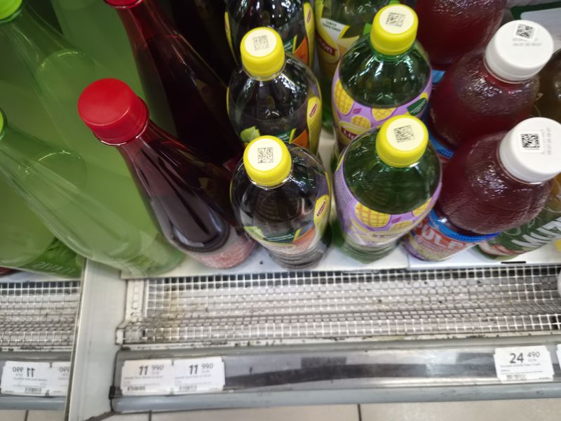 Верхний ряд напитков: бутылки Lipton, Flavis, Mutti, Pulpy с крышками-QR; внизу на кромке три размытых ценника 11 990