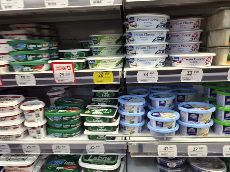 Холодильная витрина с творожными сырами Valio Cream Cheese, Kiri Labne, Pinar Labne, Hochland: ценники на кромках, красная плашка «Narxiga javob» и жёлтый акционный ценник