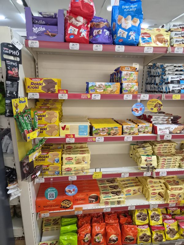 Стеллаж с вафлями: Milka, Crafers, Яшкино, Rokki Kroki, «Коровка», 365 kun, «Из Корзинки», Biscolata, Bruni; ценники на красных кромках, плашки «Yanada arzon narx!» и жёлтые ценники