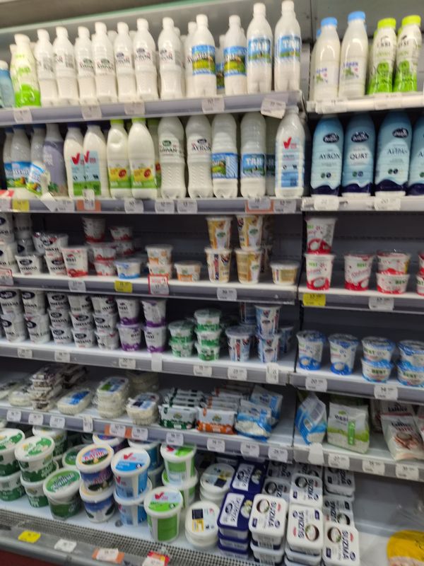 Холодильная стойка с кисломолочными продуктами: айран и кефир в бутылках (Доброе, TAN, Essi, 365 kun), творог и сметана в стаканах, творог в пакетах; ценники на кромках нерезкие