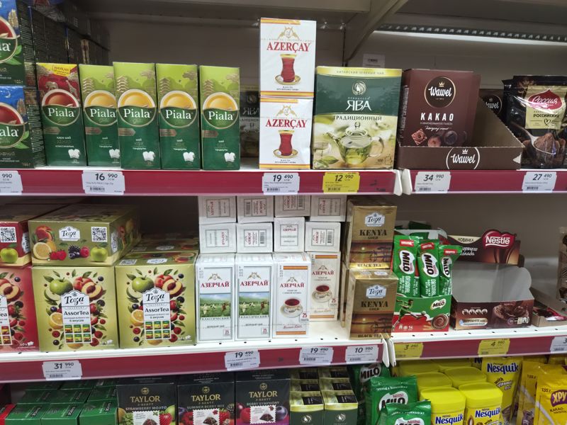 Полки с чаем Piala Gold, Азерчай, «Принцесса Ява», Toza, какао Wawel, Nestle Milo и Nesquik; жёлтые ценники «Hafta super narxlari»