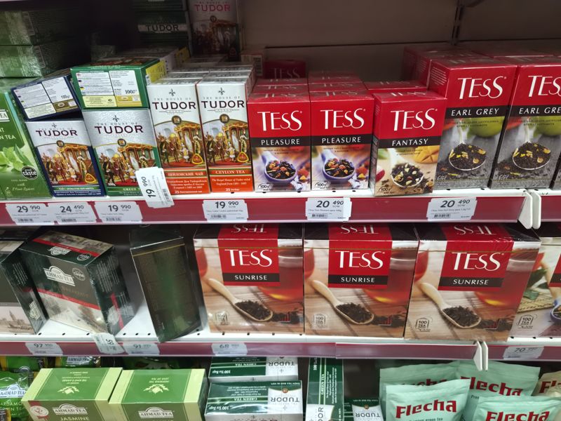 Полки с чаем Tudor (Earl Grey, зелёный, Ceylon), Tess, Ahmad Tea; ряды ценников; два ценника повёрнуты вертикально