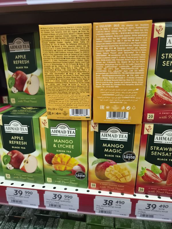 Крупный план чаёв Ahmad Tea: Apple Refresh, Mango & Lychee, Mango Magic, Strawberry Sensation; над ними две пачки повёрнуты обратной стороной со штрихкодами; внизу ценники