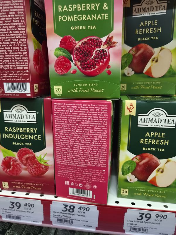 Крупный план чаёв Ahmad Tea: Raspberry Indulgence, Raspberry & Pomegranate (повёрнута обратной стороной), Apple Refresh; внизу ценники со штрихкодами