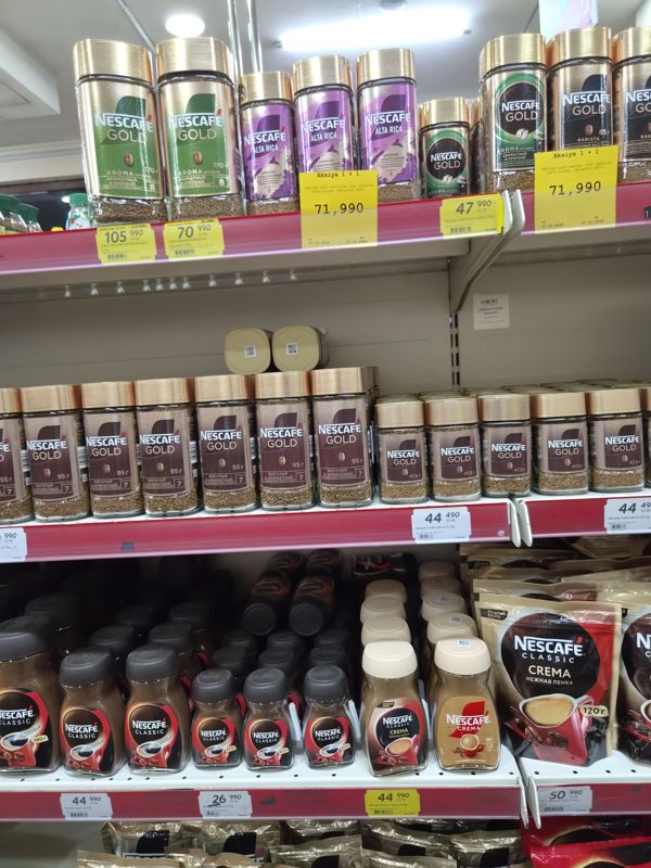 Полки с Nescafe: Gold Barista, Gold Aroma Intenso, Alta Rica, Gold 95 г и 47,5 г, Classic, Classic Crema; жёлтые ценники и две большие карточки «Aksiya 1 + 1»