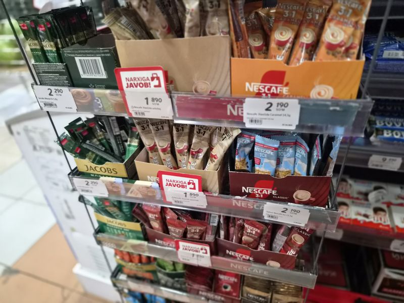 Стойка со стиками кофе: Jacobs Monarch, Nescafe 3 в 1 (Mild, Caramel, Ice, Classic), красные плашки «Narxiga javob!» на ценниках по 1 890