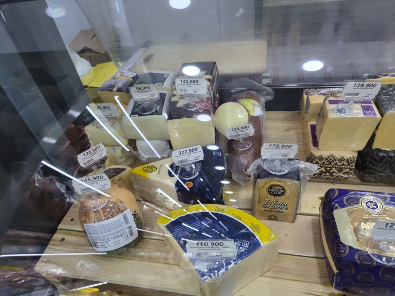 Витрина с весовыми сырами: моцарелла Oldenburger и Bonfesto, голубые и пряные сыры, «Дваро», колбасный копчёный, Grana Padano, «Прима Гранде», «Нежный», «Алиса», сыр «Мальбер», Королевский; ценники Сырной лавки