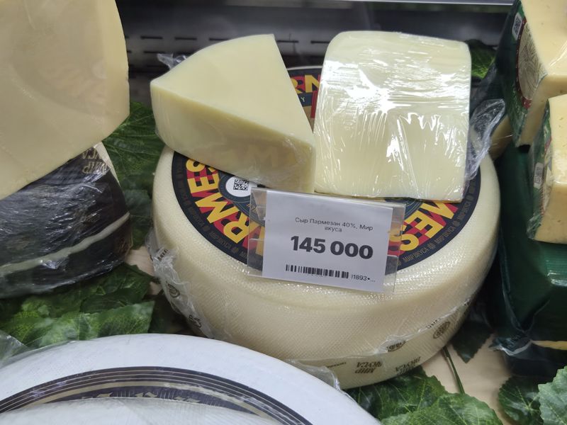 Круг сыра Пармезан «Мир вкуса» с головой и куском в плёнке сверху, ценник с ценой и артикулом