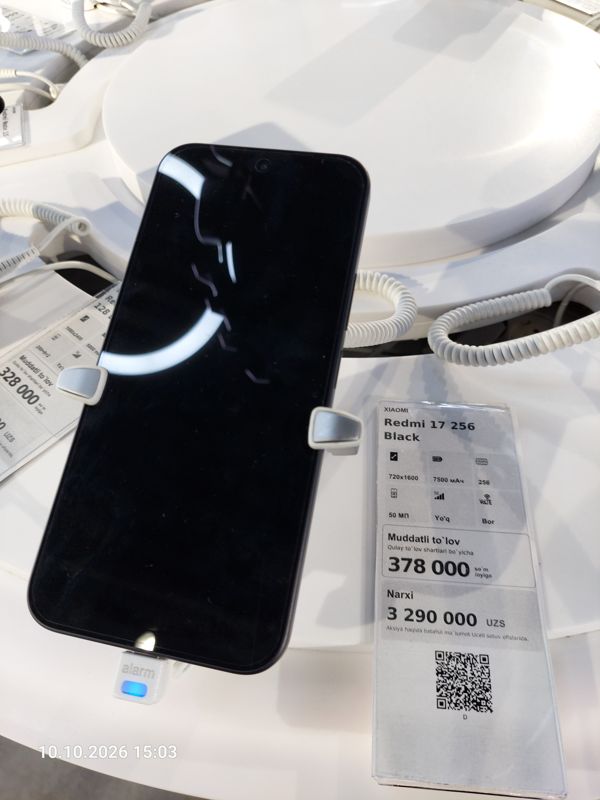 Смартфон Xiaomi на витрине Ucell в держателе с сигнализацией, рядом ценник-карточка: XIAOMI Redmi 17 256 Black, 3 290 000 сум