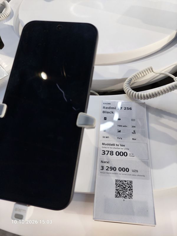 Смартфон Xiaomi на витрине Ucell в держателе с сигнализацией, рядом ценник-карточка «Redmi 17 256 Black», 3 290 000 сум