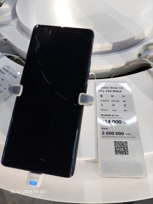 Смартфон Xiaomi на витрине Ucell в держателе с сигнализацией, рядом ценник-карточка: XIAOMI Redmi Note 14 Pro 256 Black, 3 600 000 сум