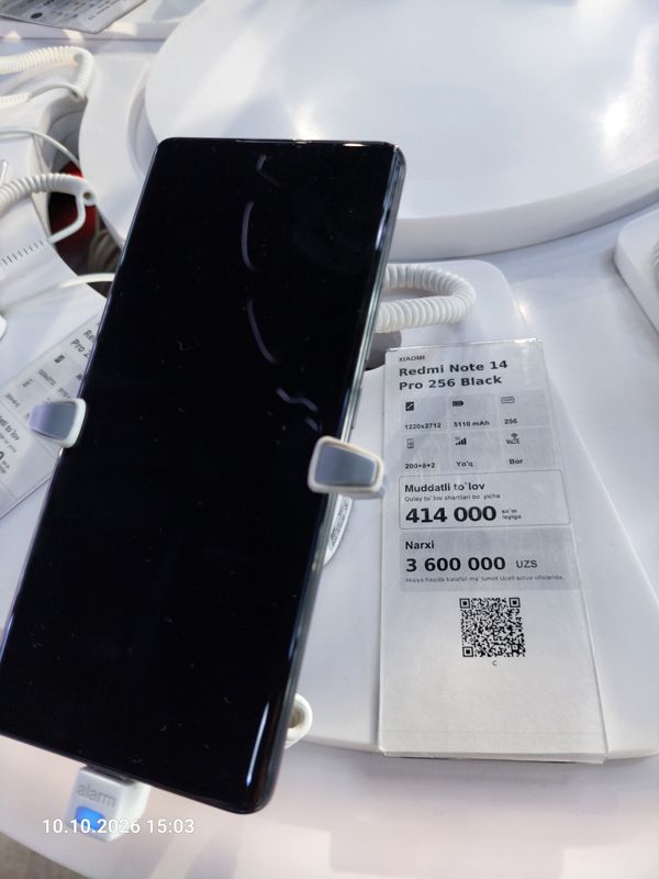 Смартфон Xiaomi на витрине Ucell в держателе с сигнализацией, рядом ценник-карточка: XIAOMI Redmi Note 14 Pro 256 Black, 3 600 000 сум