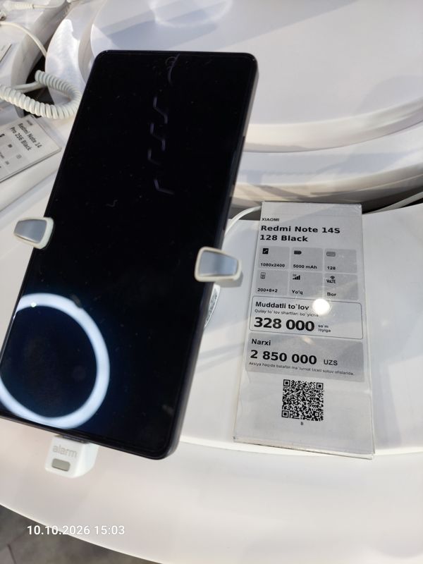 Смартфон Xiaomi на витрине Ucell в держателе с сигнализацией, рядом ценник-карточка: XIAOMI Redmi Note 14S 128 Black, 2 850 000 сум