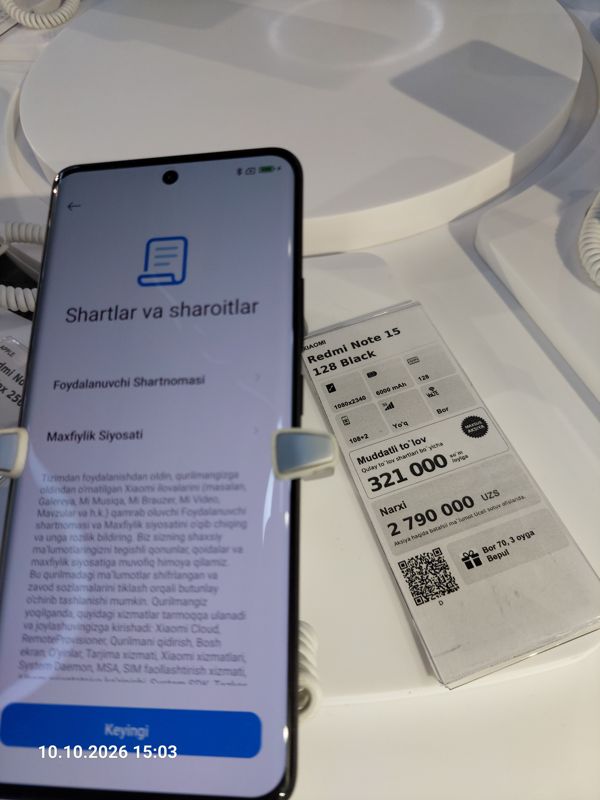 Смартфон Xiaomi на витрине Ucell в держателе с сигнализацией, на экране условия использования, рядом ценник-карточка: XIAOMI Redmi Note 15 128 Black