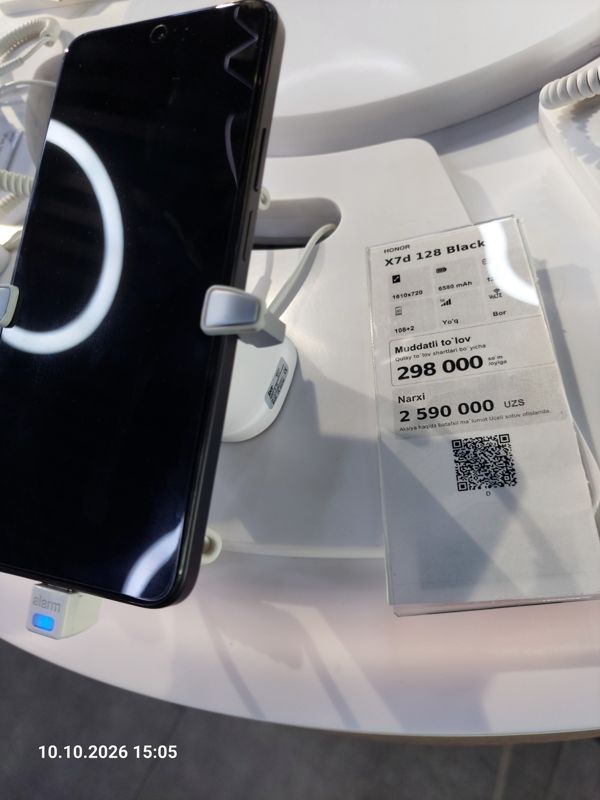 Смартфон Honor X7d в держателе с сигнализацией на витрине Ucell, рядом ценник-карточка: HONOR X7d 128 Black, 2 590 000 сум