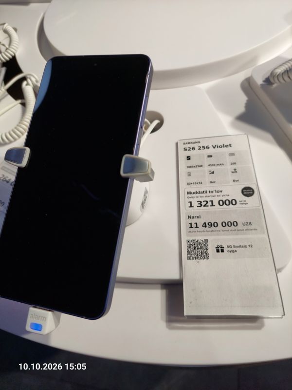 Смартфон Samsung Galaxy S26 в держателе с сигнализацией на витрине Ucell, рядом ценник-карточка: SAMSUNG S26 256 Violet, плашка «Maxsus aksiya» и подарок «5G limitsiz 12 oyga», 11 490 000 сум